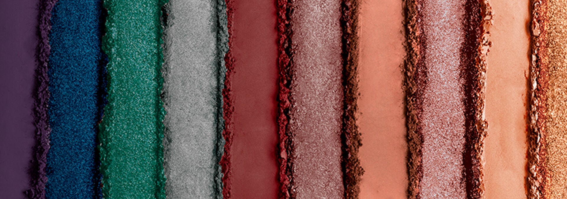 Banner com fundo em tons de roxo, azul, verde e vermelho e outras cores, apresentando sombras em pó. O texto sugere transformar o olhar com texturas suaves e durabilidade para qualquer ocasião.