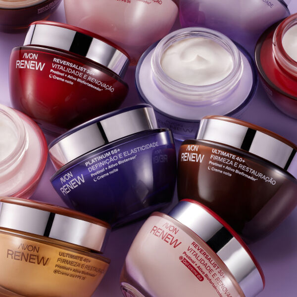 Linha Avon Renew reunida sob fundo roxo iluminado. Exibe potes de cremes faciais em tons de vermelho, dourado e azul, um deles aberto mostrando a textura cremosa do produto.