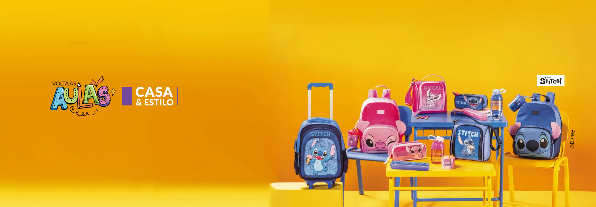 Mochilas, lancheiras, estojos e garrafas azul e rosa dos personagens Stitch e Angel sobre mesas e cadeiras azul e amarelo. Logos “Volta às aulas”, “Casa & Estilo” e “Disney Stitch”. Fundo amarelo.