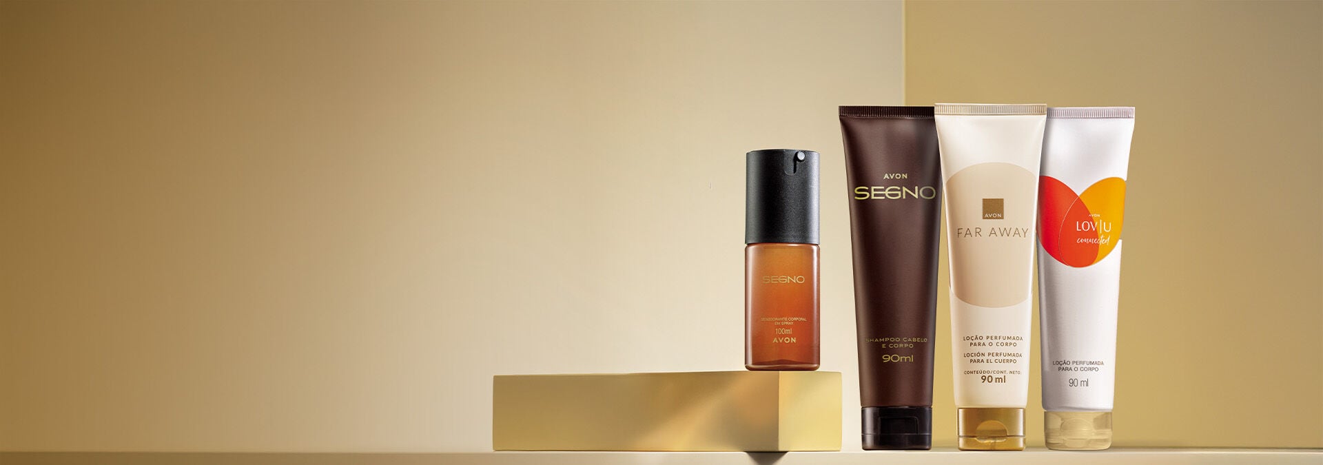 Banner com fundo dourado. Elementos incluem perfume Segno, shampoo Segno e loção Far Away sobre uma base dourada. Texto: "Corpo e Banho: presentes Avon para todos, da lembrancinha ao presentão."
