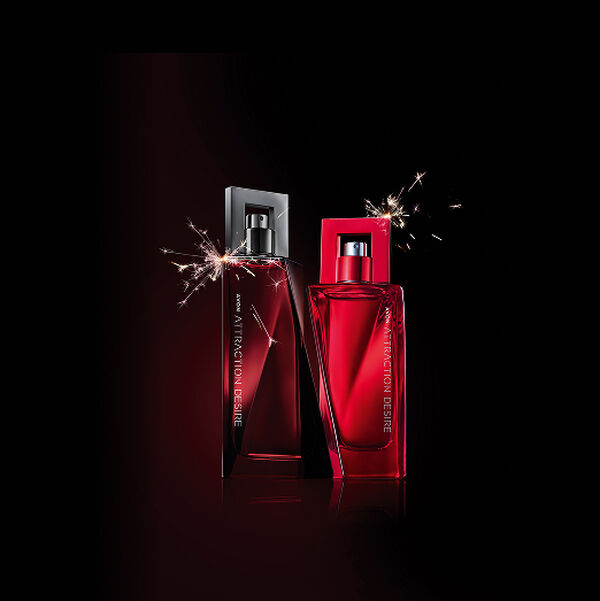 Frasco vermelho-escuro de Attraction Desire Para Ele Deo Colônia e frasco vermelho do Attraction Desire Para Ela Deo Parfum com faiscas ao redor. Fundo preto. 