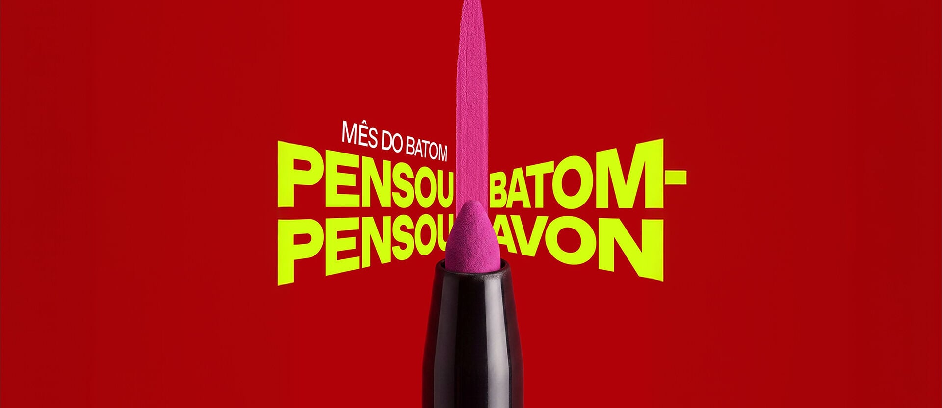 Batom rosa vibrante deixa uma pincelada vertical sobre fundo vermelho. Ao fundo, destaque para a promoção "Mês do Batom: Pensou Batom Pensou Avon”