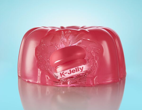 Embalagem Avon Balm Multifuncional K-Jelly dentro de gelatina rosa. Fundo azul-claro.
