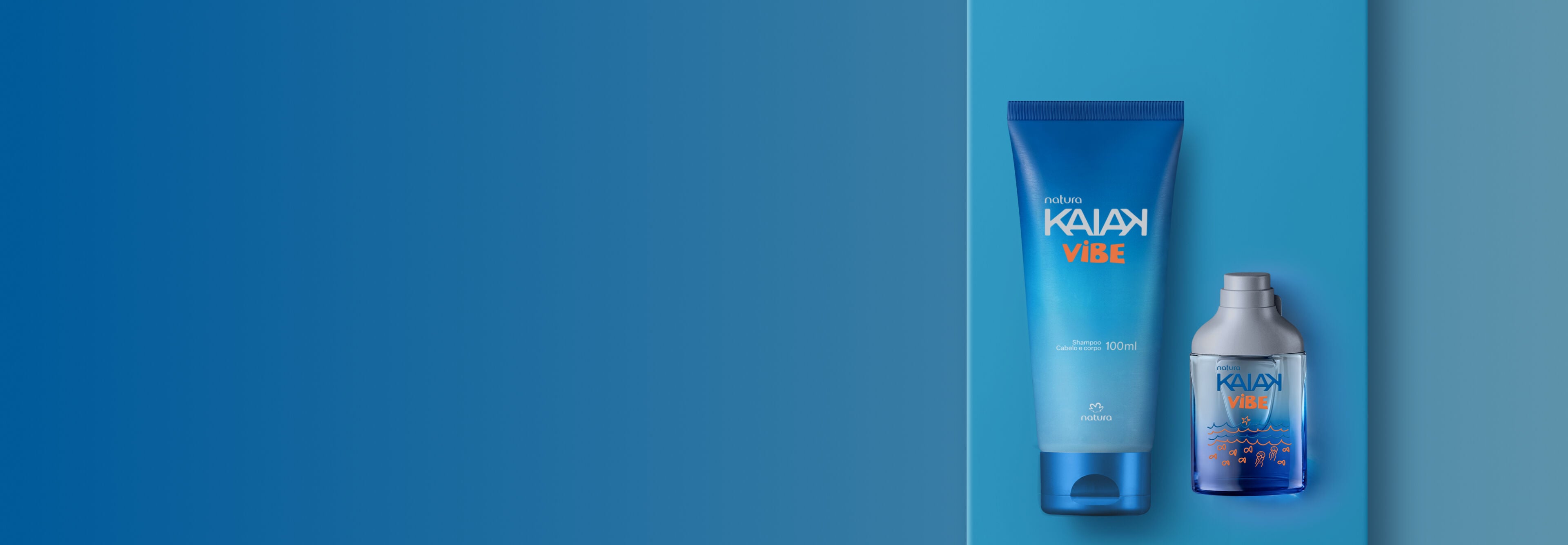 Shampoo para cabelo e corpo em bisnaga azul e perfume Natura Kaiak Vibe dispostos sobre superfície azul. O frasco transparente exibe líquido azul com ilustrações de ondas e peixes.