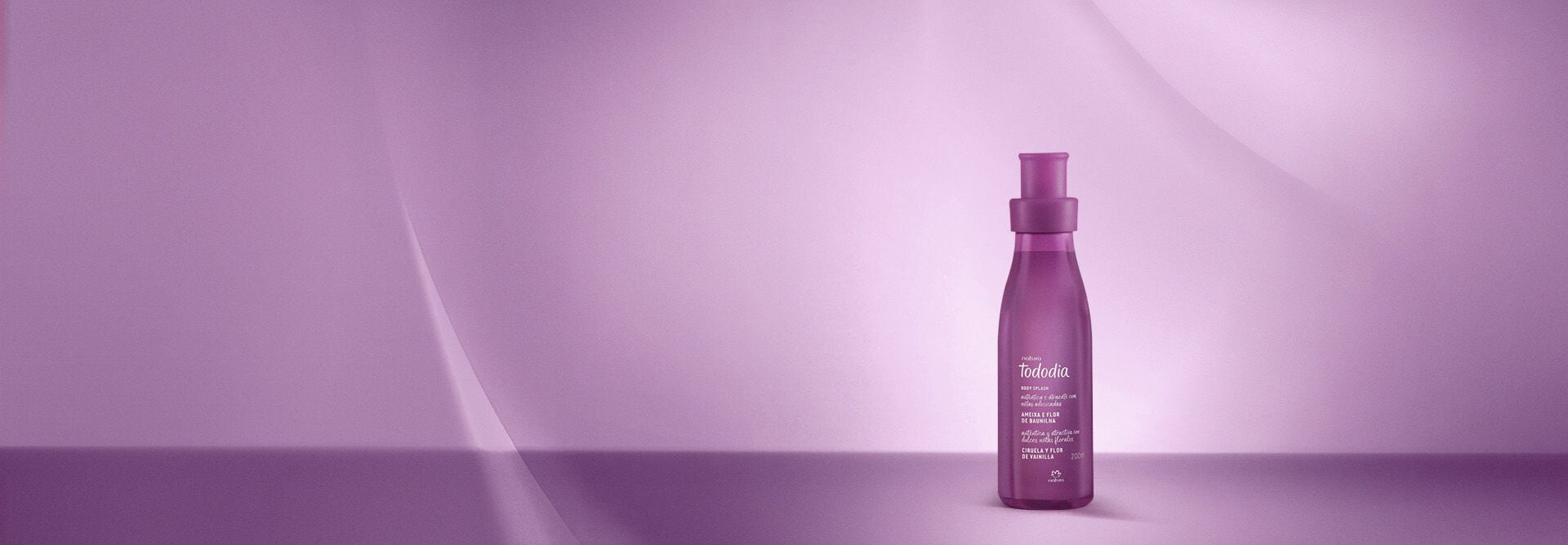 Óleo Bifásico Corporal Tododia Ameixa e Flor de Baunilha em frasco translúcido, com tampa roxa e líquido roxo e laranja dentro. Está em fundo lilás.