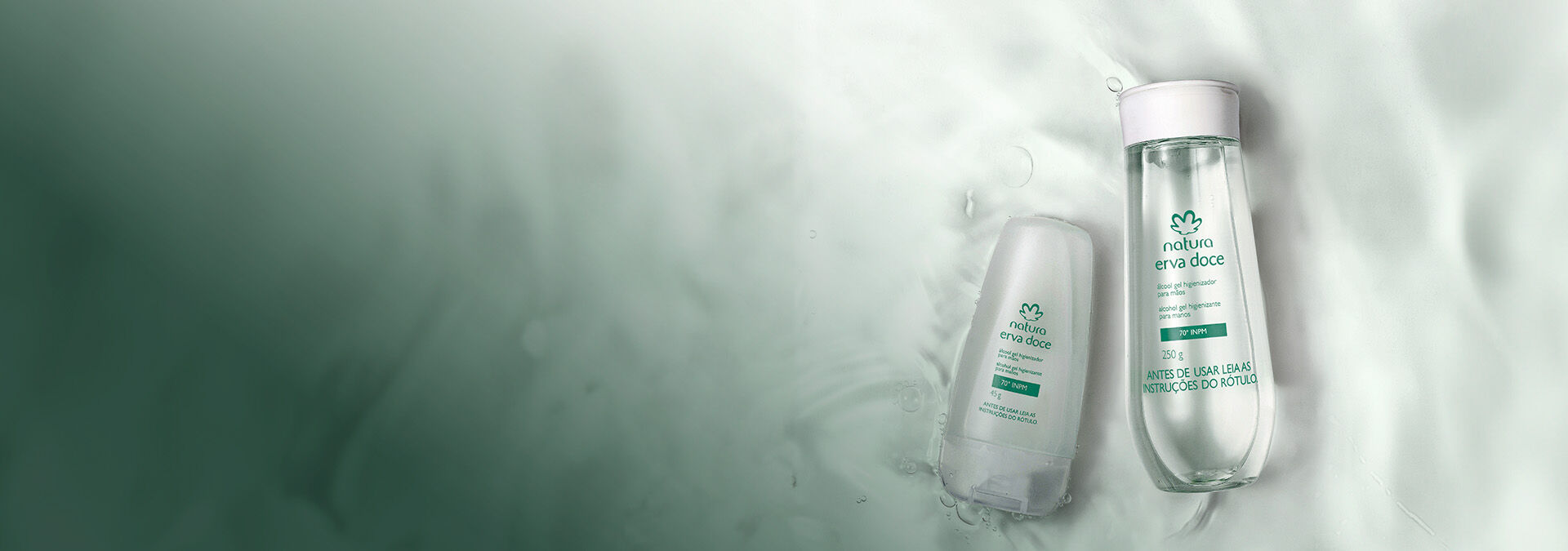Dois frascos de álcool gel higienizador de Natura Erva Doce imersos em água cristalina, transmitindo frescor e delicadeza.
