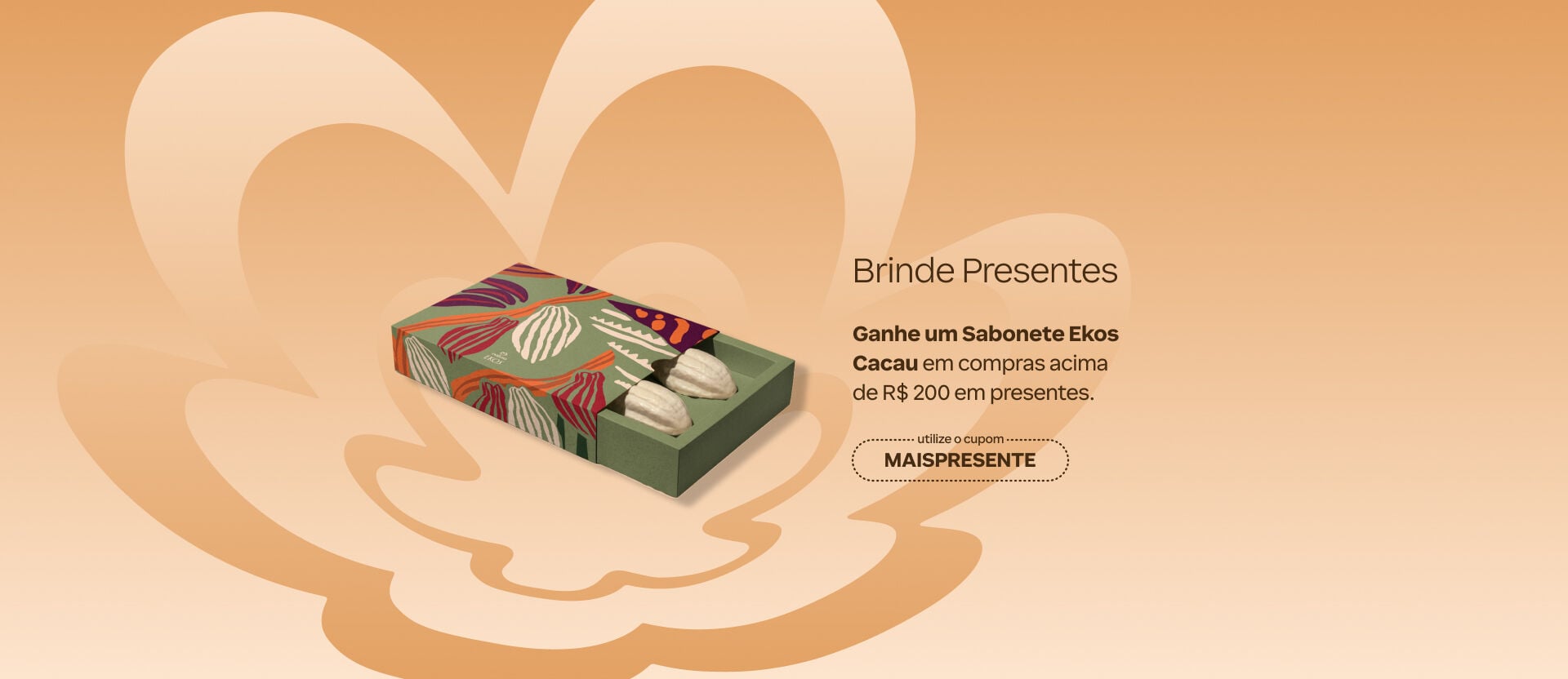 Fundo em degradê alaranjado com caixa de sabonetes em formato de cacau. Texto: "Brinde Presentes. Ganhe um Sabonete Ekos Cacau em compras acima de R$200 em presentes". Cupom: MAISPRESENTE. 