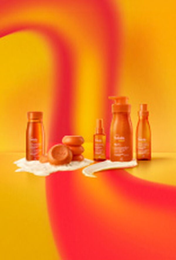Em fundo em tons de laranja e amarelo, produtos da linha Natura Tododia Energia: Sabonete Líquido e sabonetes com espuma, Bruma Facial, Loção Corporal com textura e Body Splash.