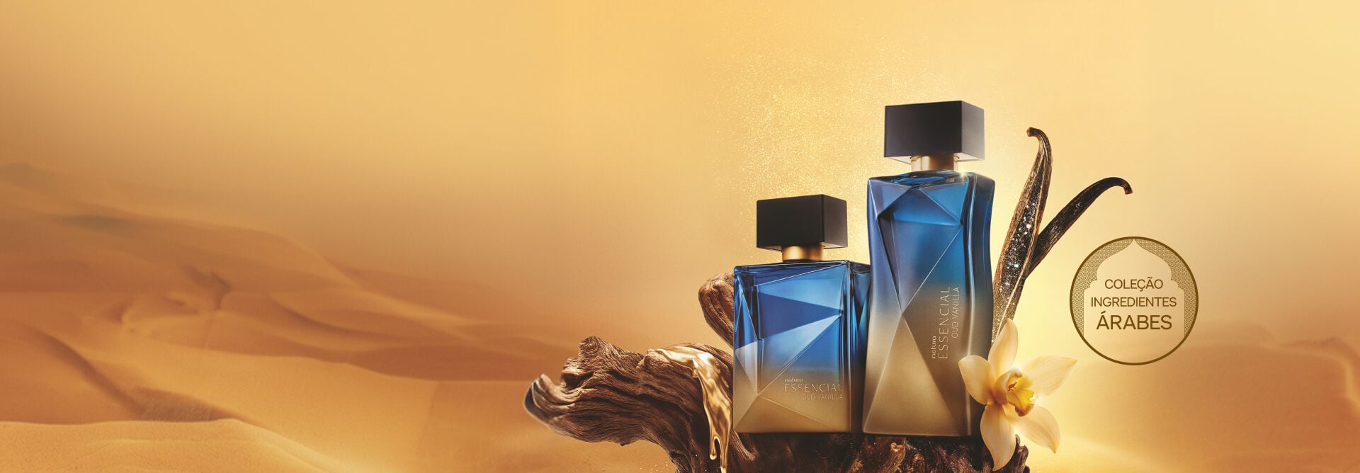 Frascos dos Deo Parfums Essencial Oud Vanilla Masculino e Feminino sobre madeira com líquido dourado, ao lado de favas de baunilha em um cenário de deserto. Contém selo: "Coleção Ingredientes Árabes".