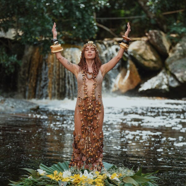 A cantora Anitta em uma cachoeira sobre oferenda floral