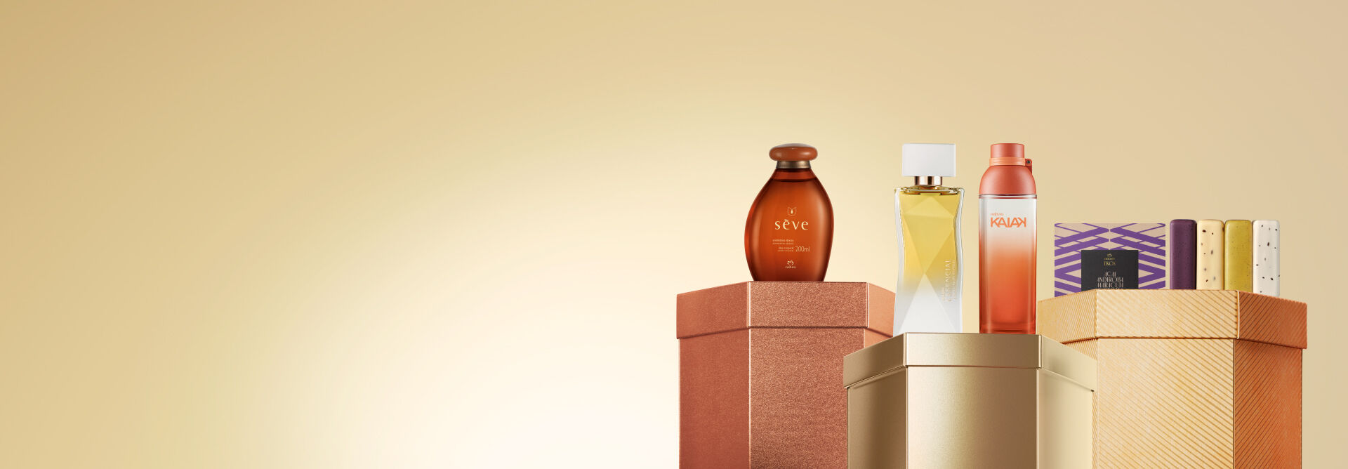 Embalagens Natura sobre caixas brilhantes marrom, dourada e laranja, em fundo amarelo: frasco de óleo Sève, fragrâncias Essencial Exclusivo Floral e Kaiak, e caixa com sabonetes em barra Ekos.