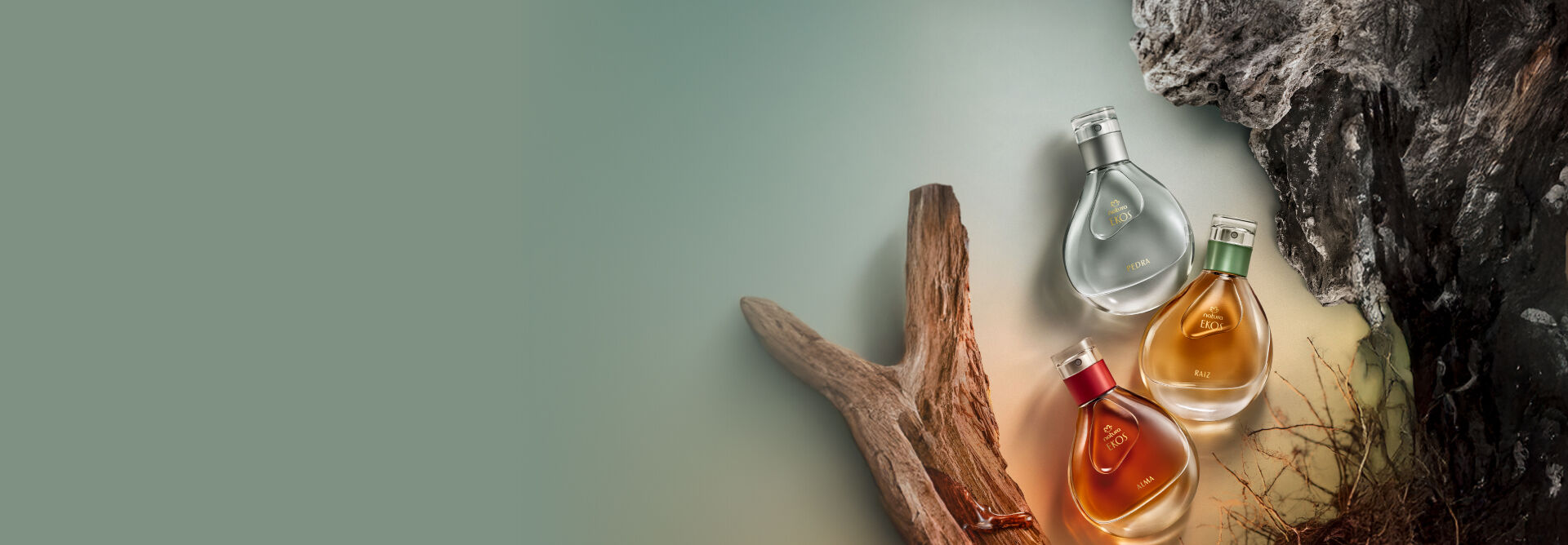 Frascos de fragrâncias Natura Ekos nas cores cinza, amarelo e vermelho, com elementos naturais, como madeiras, raízes e pedras, em fundo em tons de verde-claro.