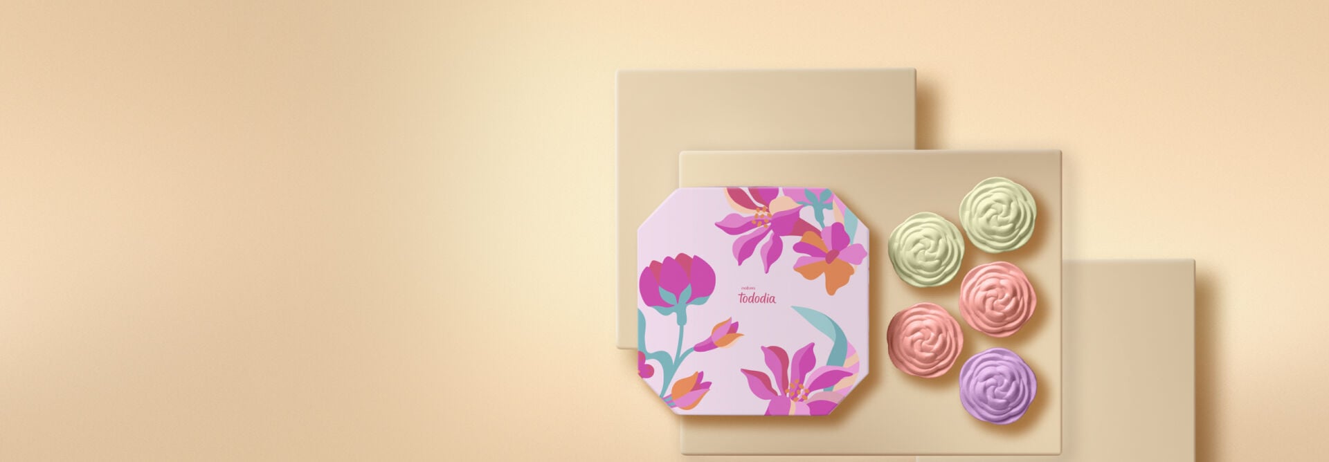 Caixa de sabonetes em barra Natura Tododia com estampa floral rosa, roxa e verde ao lado de cinco sabonetes em formato de flor. Os produtos estão dispostos sobre plataformas bege em fundo suave.