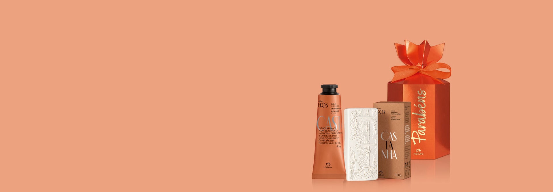 Fundo terracota com Kit Natura Ekos Castanha e embalagem de presente escrito "Parabéns"