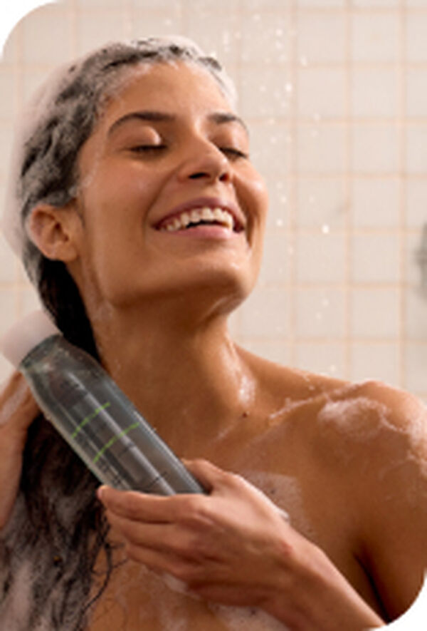 Mulher sorridente no banho com espuma no cabelo usando o Shampoo hidratante Tododia Maçã Verde e Aloe Vera
