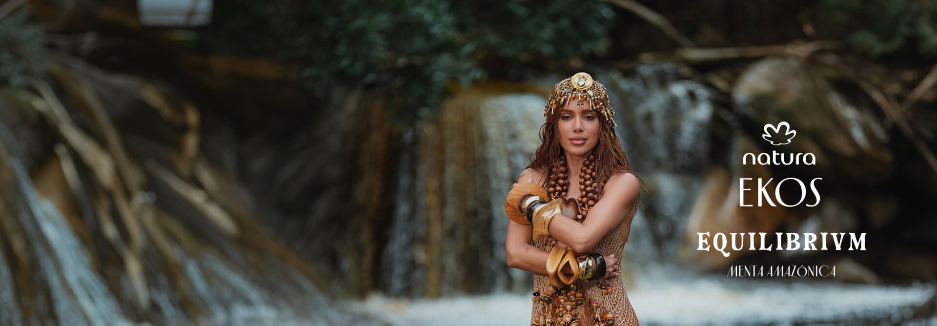 A cantora Anitta em uma cachoeira sobre oferenda floral, ao lado do logotipo Natura Ekos e do texto "Equilibrivm Tour".