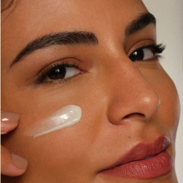 Close de foto de mulher branca com creme na bochecha.