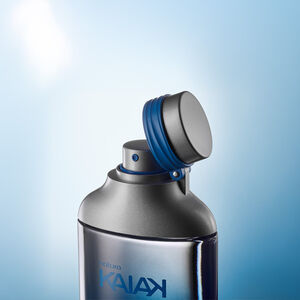 Frasco da fragrância Kaiak com tampa metálica aberta, anel azul e borrifador. Fundo degradê azul claro.