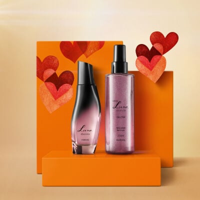 Itens Natura Luna Absoluta: frasco de fragrância e embalagem spray de Body Splash sobre caixas de presente laranja com corações vermelhos. Fundo amarelo iluminado. 
