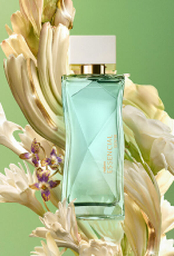 Frasco do perfume Essencial Sentir Feminino, em vidro verde com tampa dourada, posicionado ao centro, cercado por flores brancas e pequenas flores lilases, sobre um fundo em tons de verde degradê.