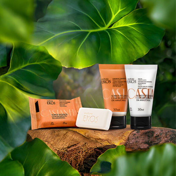 Kit Natura Ekos Castanha composto por sabonete em barra, sabonete líquido e polpa hidratante para o corpo, organizados sobre uma base de madeira rústica.