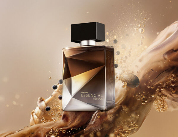 Frasco do Deo Parfum Essencial Desejos Masculino em tons de marrom e prata sobre grãos, gengibre, nozes e demais elementos que remetem aos ingredientes. Fundo marrom.