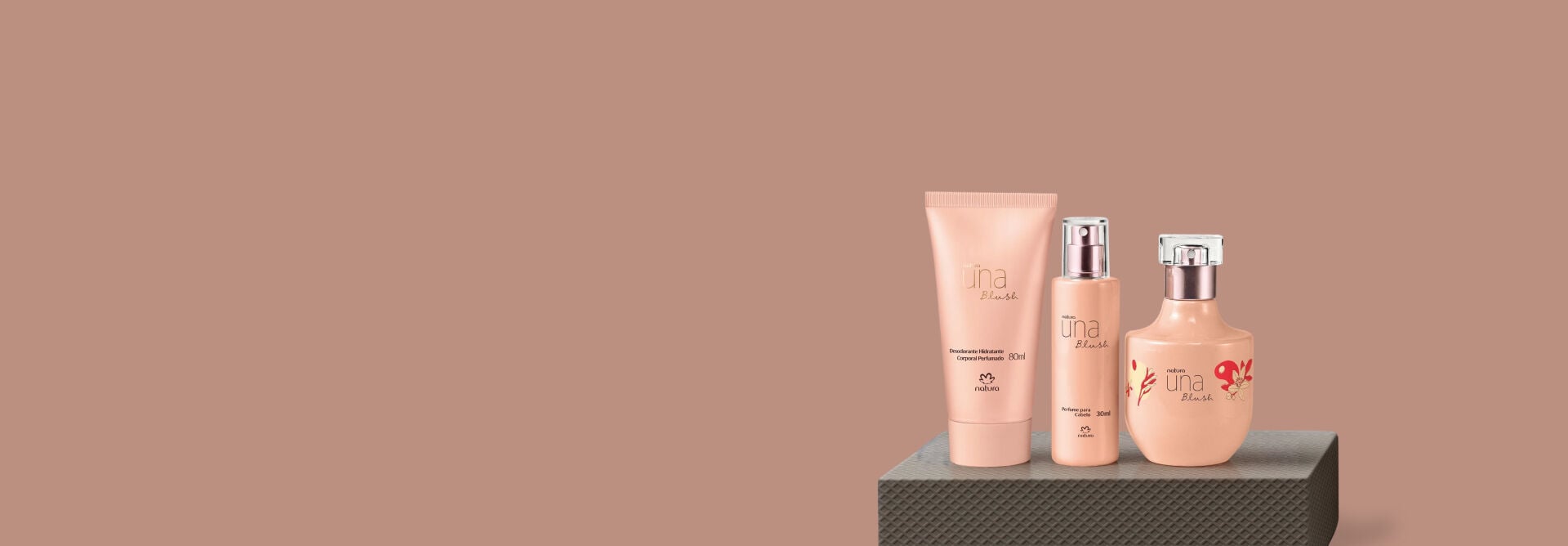 presente Natura Una Blush apoiado sobre caixa cinza em fundo rosa claro