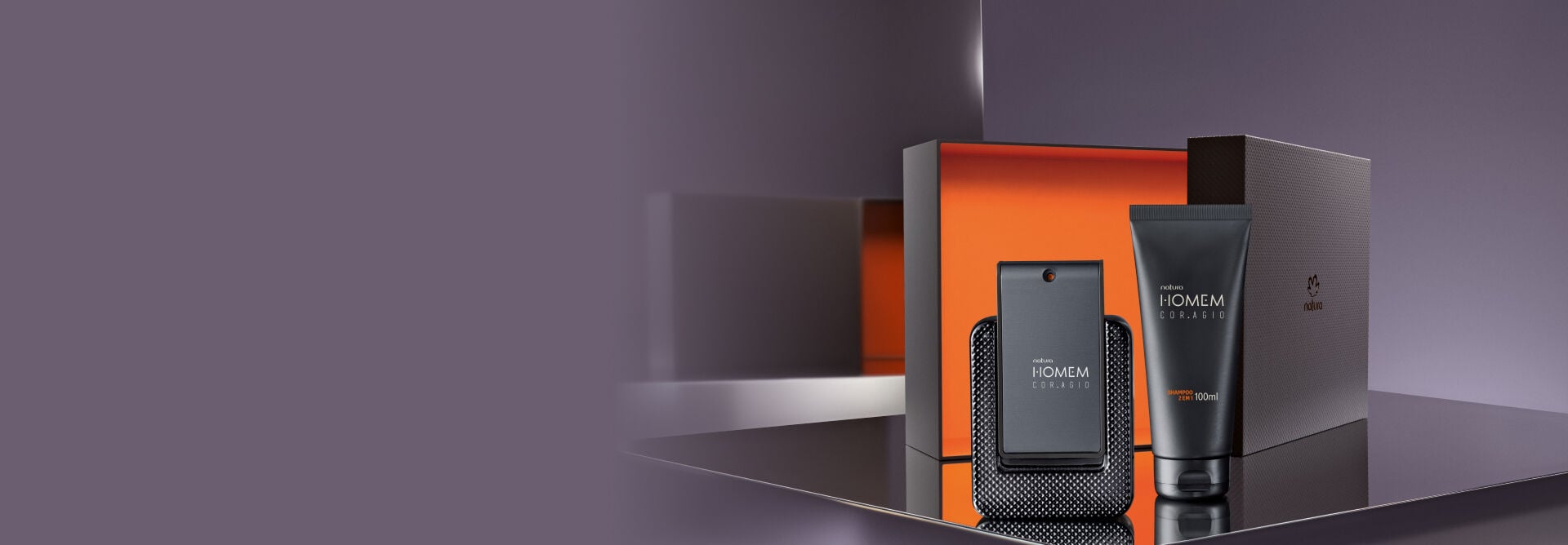 Presente Natura Homem masculino, encostados sobre uma caixa cinza e com um fundo degradê cinza