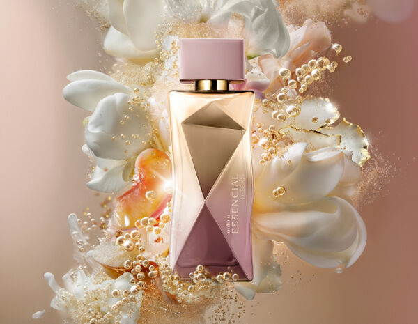 Frasco do Deo Parfum Essencial Desejos Feminino em tons de rosa e dourado sobre flores brancas, damascos e demais elementos que remetem aos ingredientes. Fundo perolado.