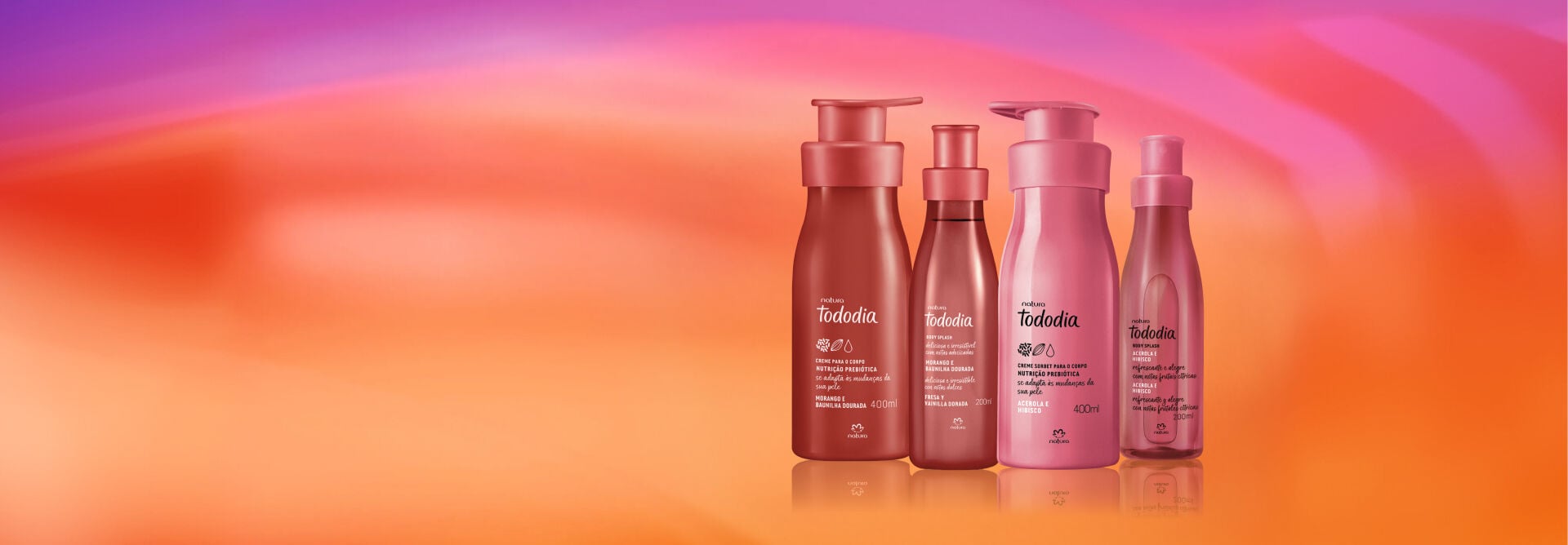 Quatro frascos de hidratantes e body splashes Natura Tododia Morango e Baunilha e Acerola e Hibisco alinhados em fundo degradê rosa e alaranjado. 