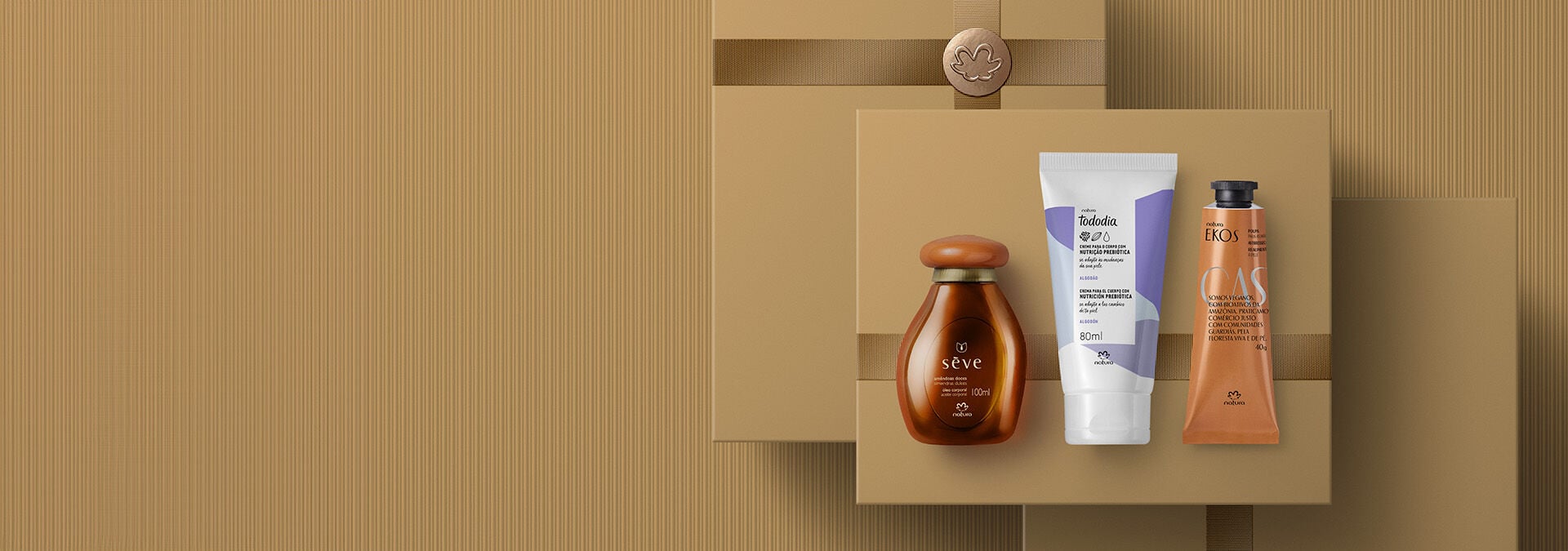 Fundo em tons de marrom: óleo corporal Natura e dois cremes para mãos sobre caixa de presente texturizada.