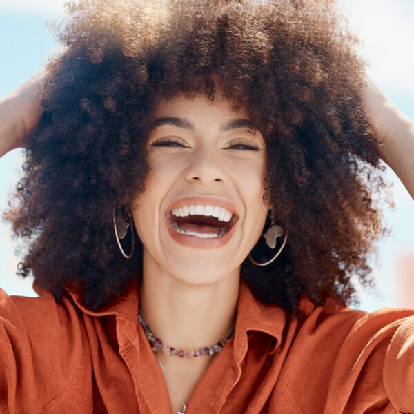 Close-up de uma mulher negra sorrindo com cabelo afro volumoso.