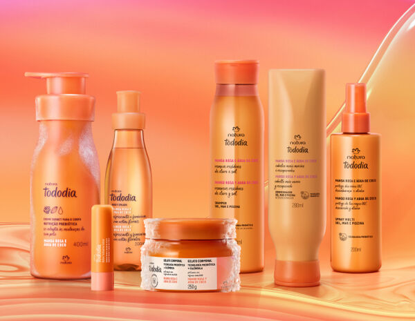 Itens Tododia Manga Rosa e Água de Coco, em laranja: frasco de Creme Sorbet, frasco de Body Splash, embalagem aberta de Balm Labial e pote de Gelato Corporal sobre grafismo e fundo em laranja.