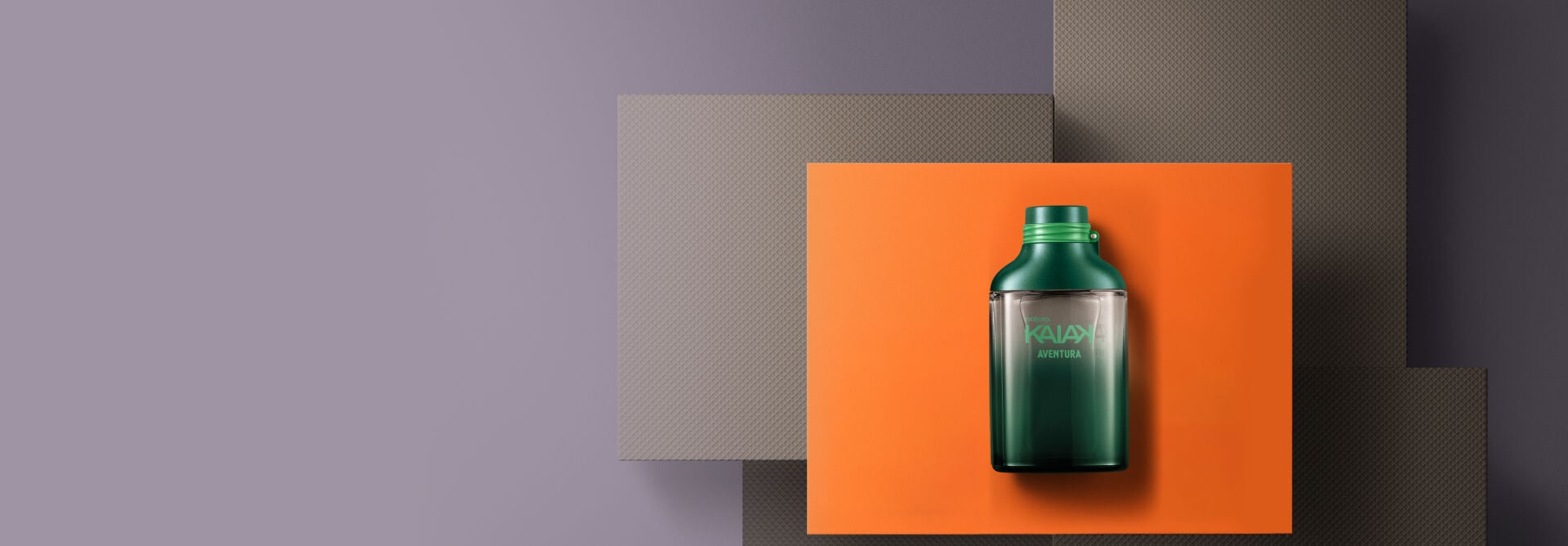 presente Natura Kaiak Aventura masculino, apoiado em uma caixa laranja, com fundo de caixas cinzas e fundo cinza