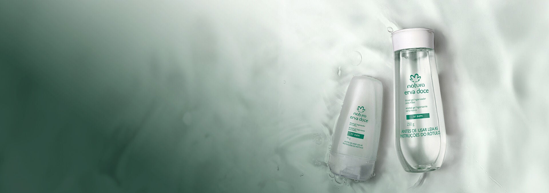 Dois frascos de álcool gel higienizador de Natura Erva Doce imersos em água cristalina, transmitindo frescor e delicadeza.