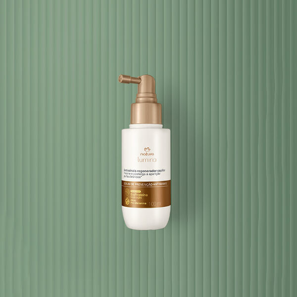 Embalagem creme com tampa e rótulo dourados de Shampoo de Tratamento Antissinais Natura Lumina. Fundo em verde com listras verticais.
