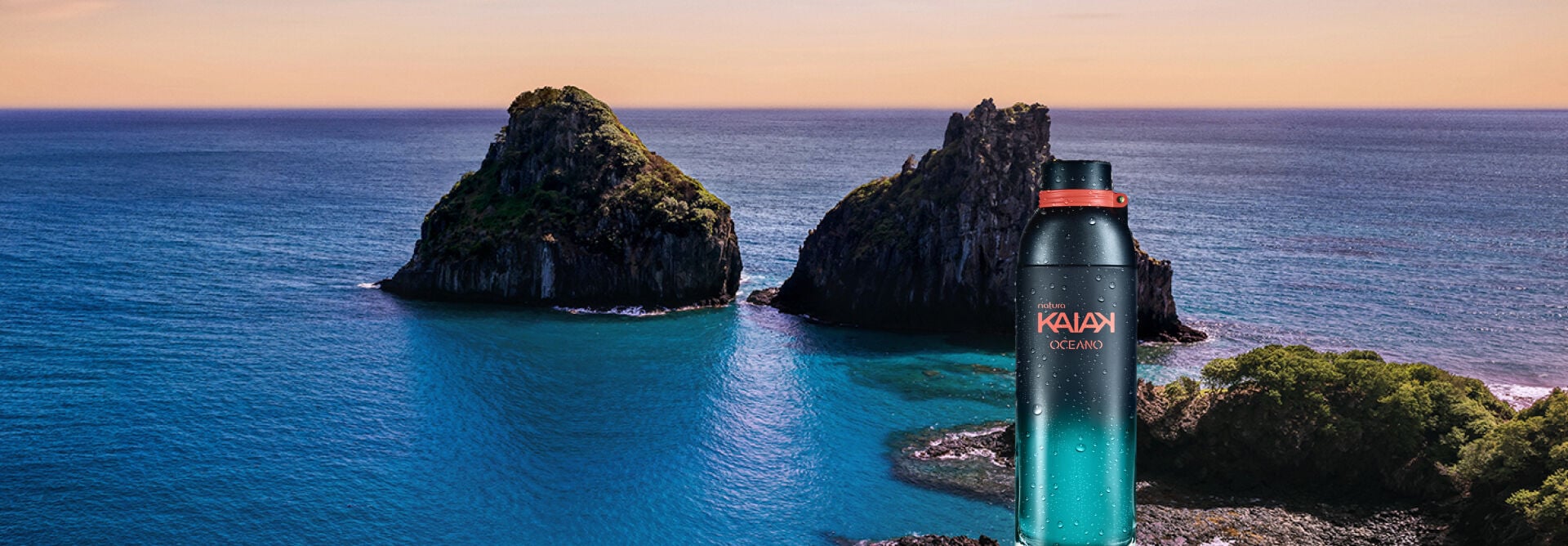 Frasco de fragrância Kaiak Oceano Feminino em fundo de horizonte marítimo com montanhas rochosas.