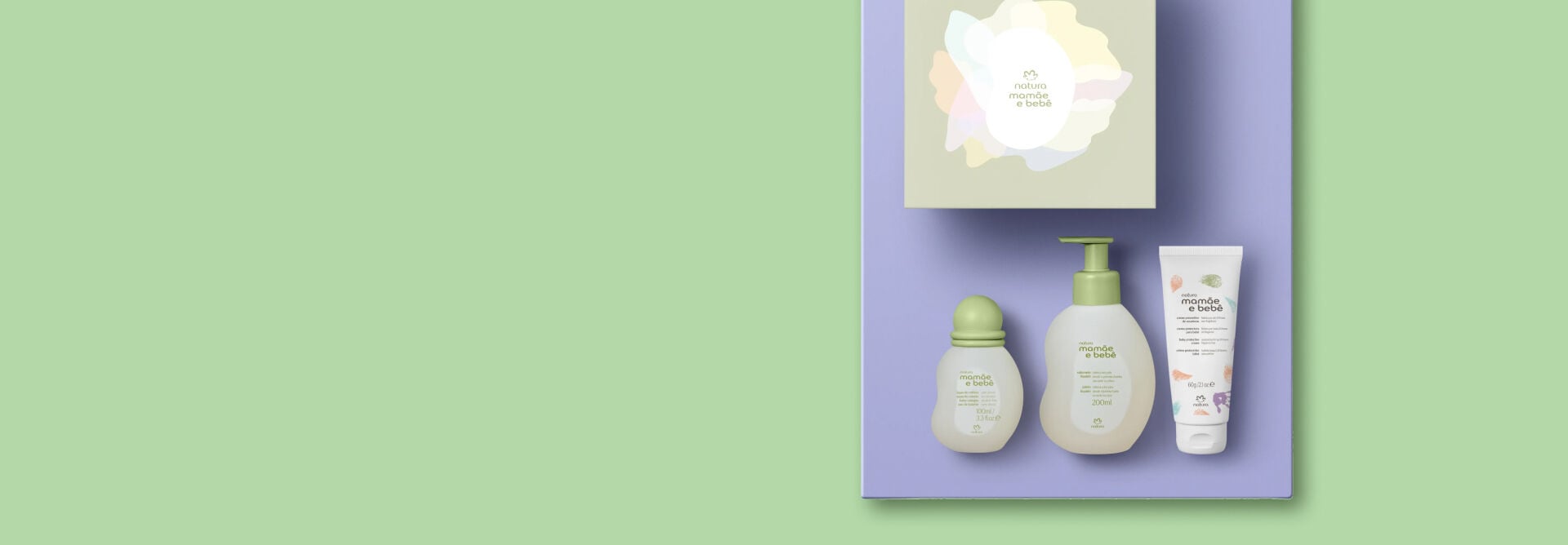 Fundo verde-claro com Kit Natura Mamãe e Bebê sobre caixa lilás: colônia, sabonete líquido, creme de assaduras e sacola.