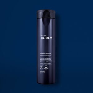 Novo Shampoo Anticaspa Natura Homem aparece em destaque no centro da tela sobre fundo azul-marinho.