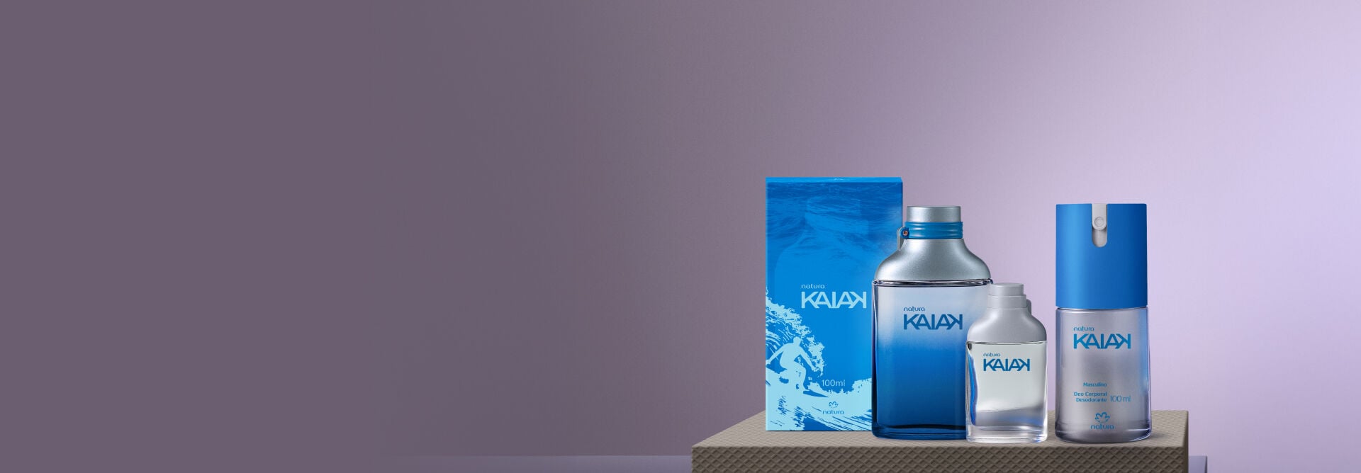 Presente Natura Kaiak masculino, apoiados sobe uma caixa cinza e com um fundo degradê cinza