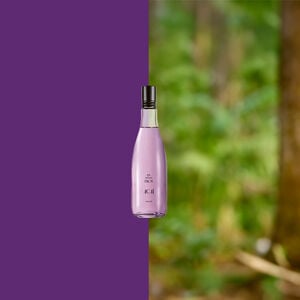 Frasco lilás do Desodorante Colônia Ekos Açaí centralizado, com metade do fundo roxo e metade mostrando floresta desfocada, sugerindo conexão com a natureza.