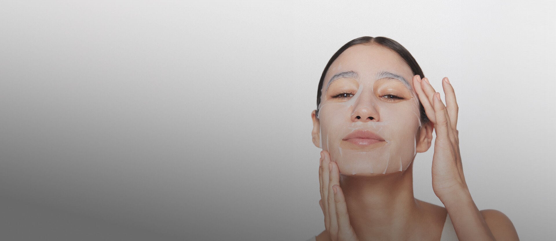 Imagem de mulher com máscara facial Natura Faces, à direita, em fundo branco.