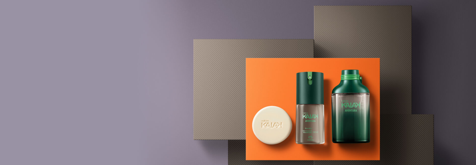 Fundo cinza e laranja com Kit Natura Kaiak Aventura: sabonete em barra, desodorante corporal e fragrância.