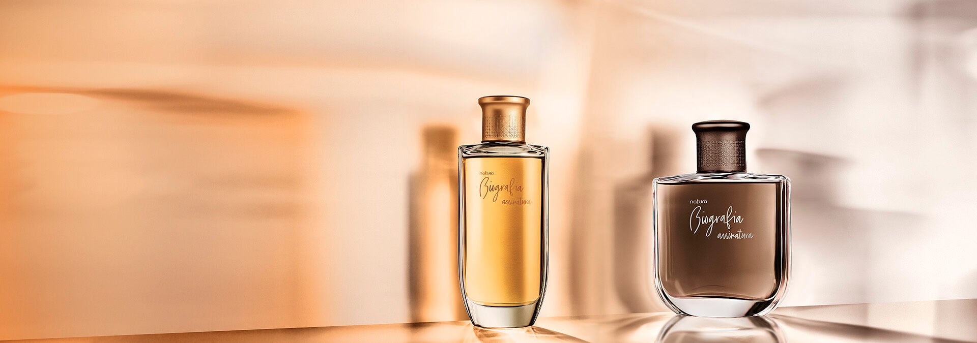 Imagem com reflexos em dourado e marrom e as fragrâncias masculina e feminina da linha Biografia assinatura