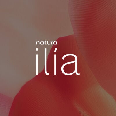 Logo de Natura Ilía, em letras brancas, destaca-se no centro da tela sobre pétalas laranjas em fundo pêssego.