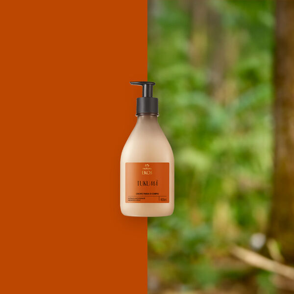 Frasco bege com pump preto do Creme Desodorante Hidratante para o Corpo Natura Ekos Tukumã ao centro. Fundo dividido entre laranja terroso e floresta desfocada em tons de verde.