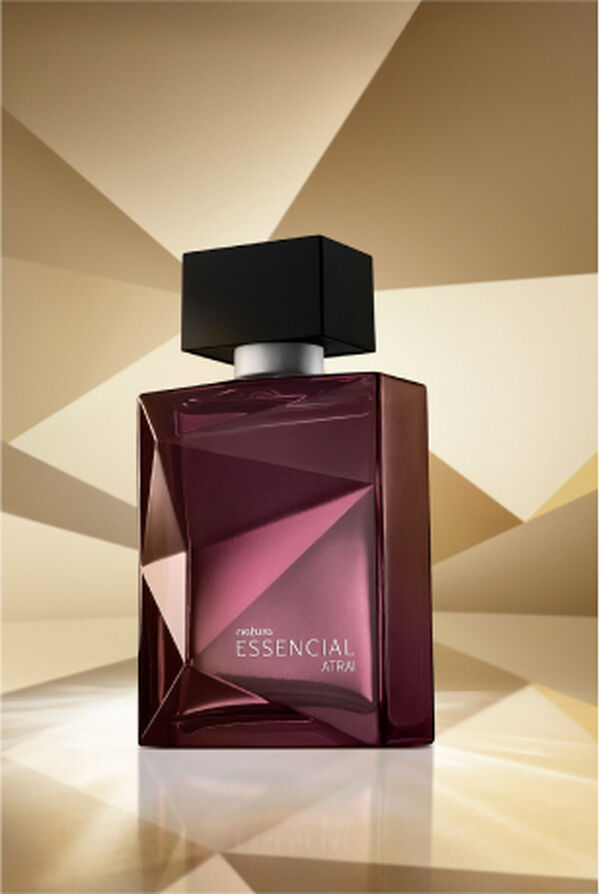 Frasco de Essencial Atrai Masculino, em tons de roxo e violeta com tampa preta, aparece em destaque em fundo dourado multifacetado, fazendo alusão ao design dos frascos de Essencial.