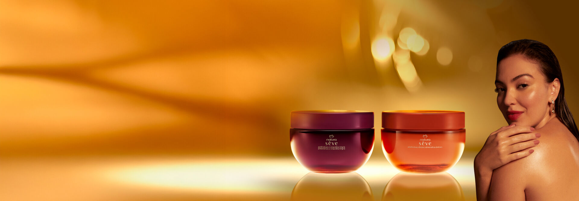Natura Sève Creme Desodorante Corporal Perfumado Amêndoas e Orquídea Negra, em tom de roxo, e Amêndoas Doces, em tom de laranja, destacam-se em superfície e fundo iluminados em tom de dourado.