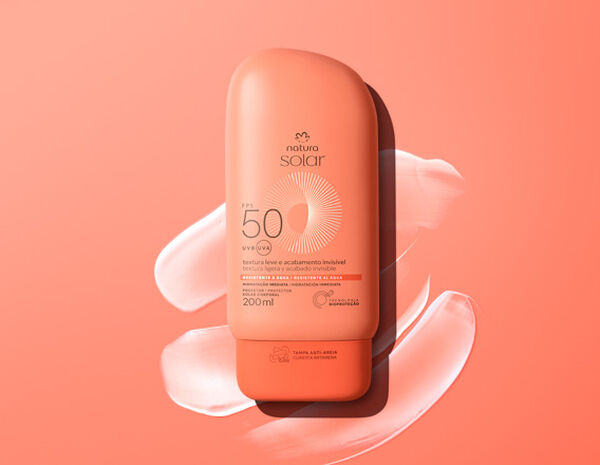 Embalagem laranja de Natura Solar Corporal FPS 50, sobre textura cremosa branca em fundo laranja.