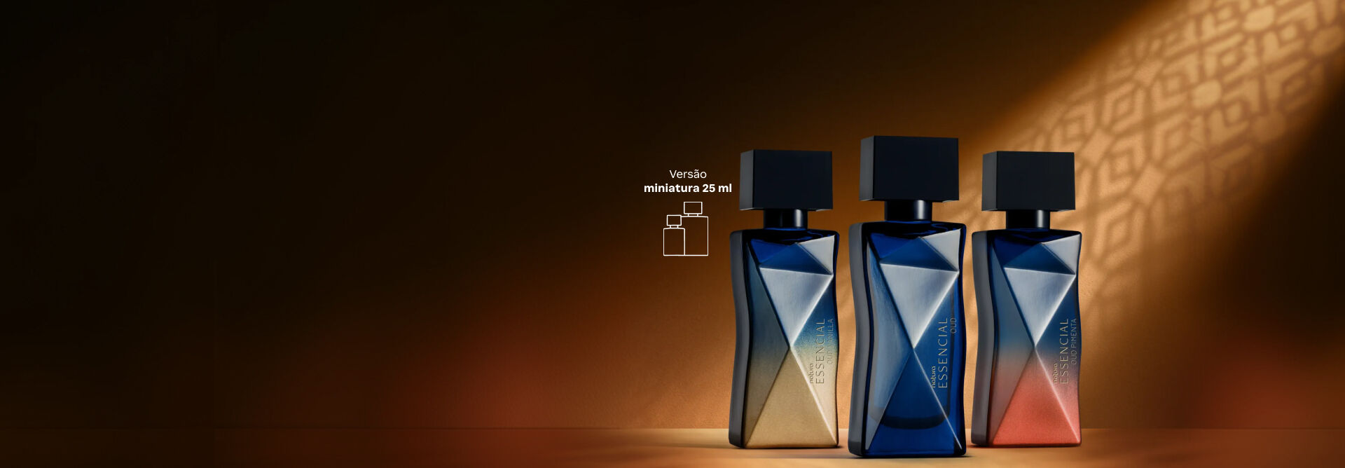 Três frascos em miniatura de 25 ml dos perfumes Natura Essencial, com frascos geométricos em tons de azul, dourado e alaranjado, sob iluminação dourada e fundo com sombra padrão. 